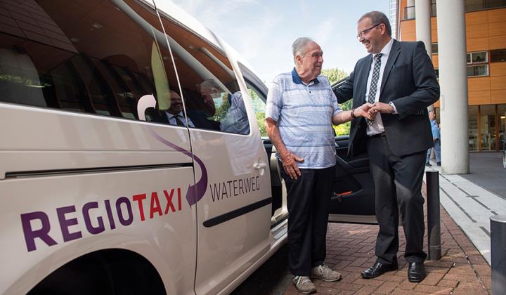 Persoon die uit de regiotaxi wordt geholpen.