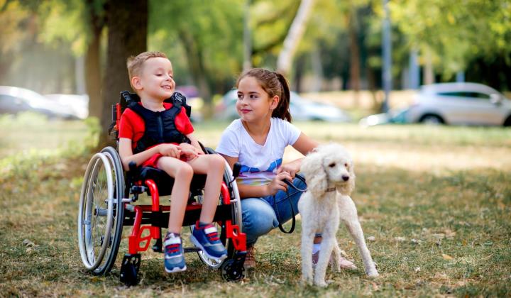 Een jongen in de rolstoel en een meisje met een hond